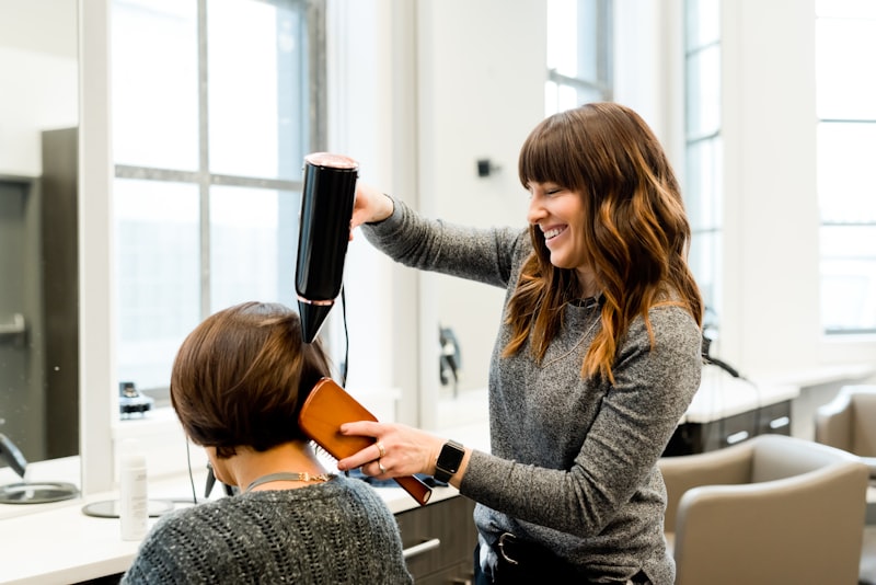 Stylist blow-drying customer hair